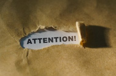 Ekonomi ve iş kavramı. Kağıdın ortasındaki yırtık kağıt, beyaz bir arkaplandaki yazı - ATTENTION