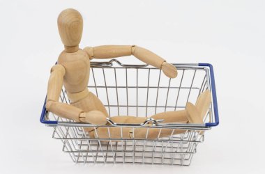 İş konsepti. Tahta adam bir alışveriş sepetinde oturur. Beyaz arkaplanda izole.