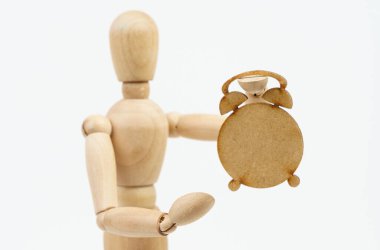 Zaman kavramı. Tahta adam elinde bir çalar saat tutuyor. Beyaz arkaplanda izole.