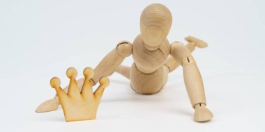 İş ve güç kavramı. Tahta adam taç için sürünüyor. Beyaz arkaplanda izole.