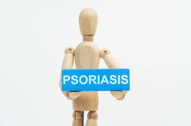 Tıp ve sağlık hizmetleri kavramı. Elinde PSORIASIS yazılı mavi ahşap bir blok tutan bir adam heykeli. Heykelcik bulanık..