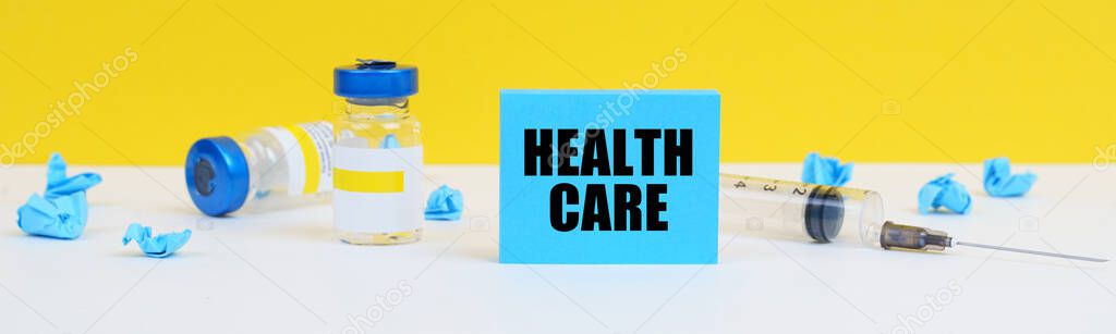 On the table is a syringe, injections and a blue sign with the inscription - HEALTH CARE
