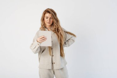 Bir kadın blogcu elinde bir tablet tutar, diğer eli ise onun tarafındadır. Bir tabletten bilgi okur.