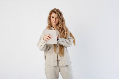 Bir kadın blogcu elinde bir tablet tutuyor, diğer eliyle sayfaları hazırlıyor. Bir tabletten bilgi okur.