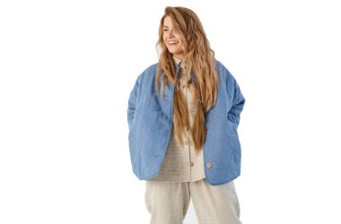 Kadın ellerini cebinde tutuyor, yan tarafa bakıyor, gülüyor. Beyaz arkaplanda izole.