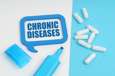 Tıbbi konsept. Beyaz ve mavi yüzeyde bir işaret, tabletler ve içinde CHRONIC DISEASES yazısının bulunduğu bir plaka var.