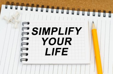 Masanın üzerinde iki defter ve bir kalem var. En üstteki not defterinde 