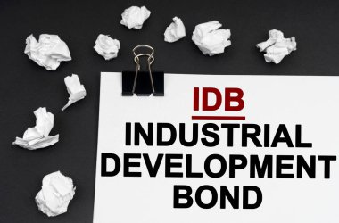 Siyah bir arkaplanda, üzerinde -IDB yazan buruşmuş kağıt ve kağıt parçaları var.