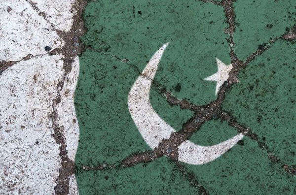 Bandeira do Paquistão em asfalto rachado. O conceito de crise, inadimplência, pandemia, conflito, terrorismo. Imagem fora de foco — Fotografia de Stock