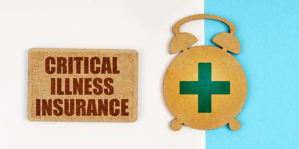 En la superficie blanca y azul hay un reloj despertador y un letrero con la inscripción - Critical Illness Insurance —  Fotos de Stock