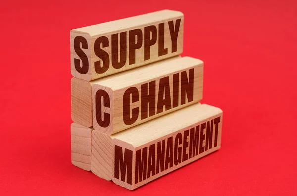 Sobre un fondo rojo, bloques de madera con la inscripción - Gestión de la cadena de suministro — Foto de Stock