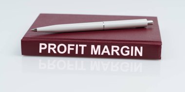 İş ve finans kavramı. Beyaz bir yüzey üzerinde bir kalem ve bir defter bulunur - PROFIT MARGIN