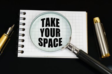 İş ve finans kavramı. Siyah bir yüzeyde bir kalem, bir defter ve bir büyüteç var. Defterdeki yazıt - Boşluğunu al