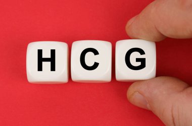 İlaçlar. Kırmızı yüzeyde HCG yazılı beyaz küpler var.