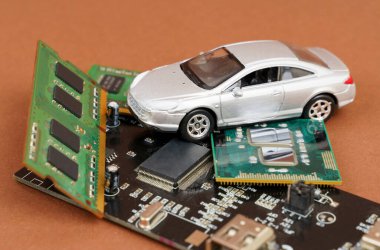 Elektronik arabalar. Mikro devrelerde, bellekte ve elektronik panelde bir araba var. Kahverengi arkaplanda izole.