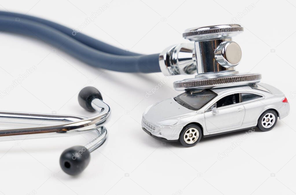 Automotive diagnostics. A stethoscope lies on the roof of a toy car. Car diagnostics, repair and maintenance concept