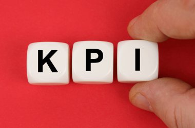 İş ve finans. Kırmızı yüzeyde KPI yazılı beyaz küpler var.