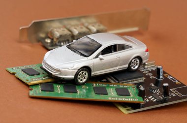 Elektronik arabalar. Mikro devrelerde, bellekte ve elektronik panelde bir araba var. Kahverengi arkaplanda izole.