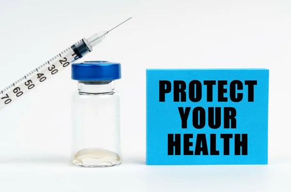 医学の概念 テーブルの上に注射器 注射器 碑文の青い看板があります あなたの健康を守る — ストック写真