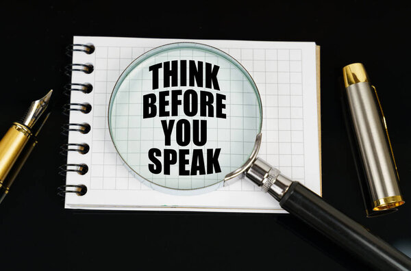 На черной поверхности есть ноутбук и увеличительное стекло. Надпись в блокноте - подумайте прежде, чем вы заговорите