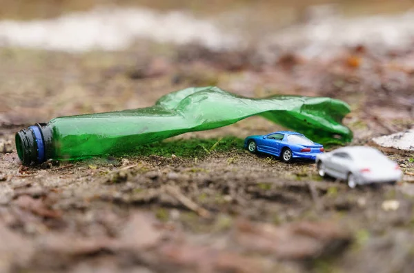 As pessoas montam seus carros de férias, passando por um arco feito de uma garrafa de plástico - um símbolo de poluição. — Fotografia de Stock