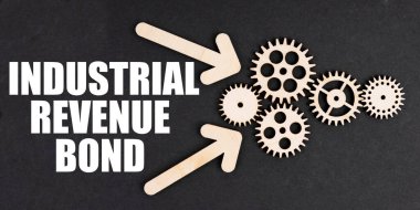 Sanayi konsepti. Siyah yüzeyde, oklar, dişliler ve bir yazıt - Endüstriyel Gelir Tahvili