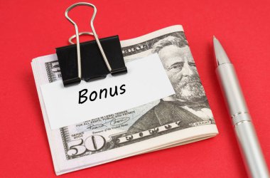 Finans ve iş konsepti. Kırmızı bir arka planda bir dolarlar ve kalem uzanır. Kağıt üzerine yazılı bir ataç ile tutturulur.