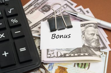 Finans ve iş konsepti. Kahverengi bir arka planda bir hesap makinesi ve bir şarjör üzerinde dolar bulunur.