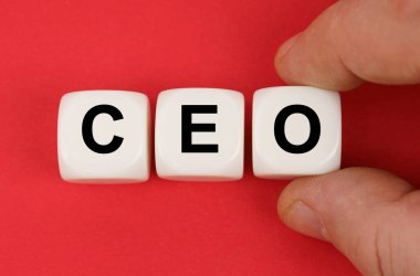 Kırmızı yüzeyde, üzerinde CEO yazan beyaz küpler var.