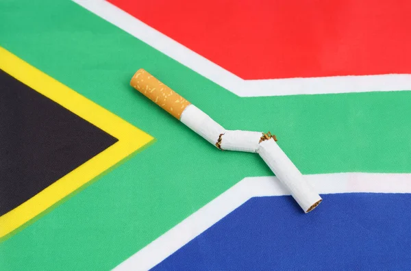 Un cigarrillo roto está en la bandera de Sudáfrica, como símbolo del daño del tabaquismo. — Foto de Stock