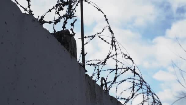 High fence with barbed wire at the top of the sky with clouds. — Stok video