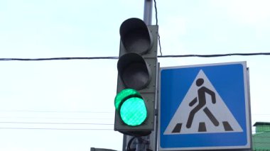 Close-up of a traffic light pedestrian crossing, the traffic light switches from green to red. City street at daytime.