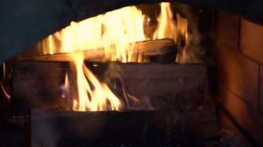 Firewood burns with a bright flame in the fireplace.