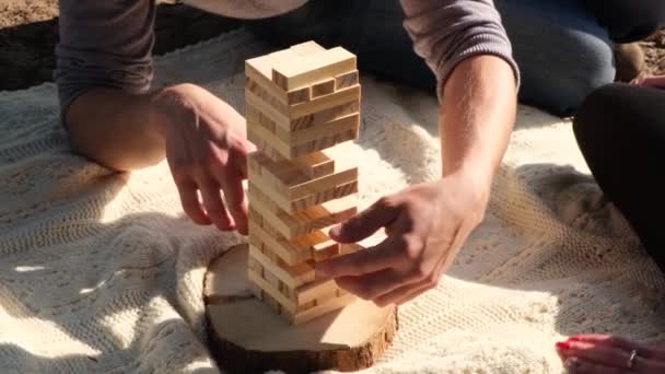 A man and a woman are playing Jenga. Close-up, only hands are visible. — Stockvideo