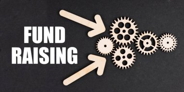 On the black surface, arrows, gears and an inscription - FUND RAISING