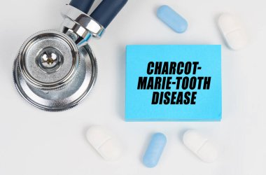 On a white surface lie pills, a stethoscope and stickers with the inscription - Charcot-Marie-Tooth disease