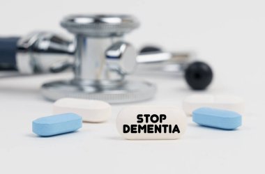 On a white surface lie pills, a stethoscope and a tablet with the inscription - STOP DEMENTIA