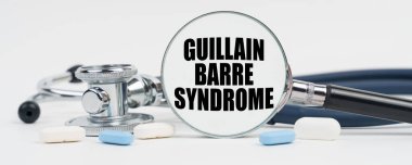 Medicine and health concept. On a white surface are pills, a stethoscope and a magnifying glass inside which is written - guillain barre syndrome