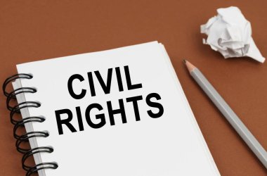 İş ve finans kavramı. Kahverengi bir yüzeyde bir kalem, buruşmuş bir kağıt ve üzerinde CIVIL hakları yazılı bir not defteri bulunur.