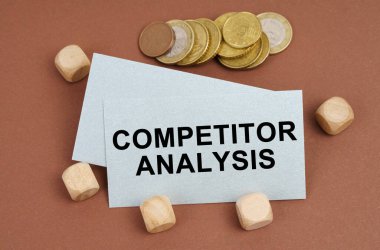 İş ve finans kavramı. Kahverengi yüzeyde sikkeler, küpler ve üzerinde COMPETITOR ANALYSIS yazan bir kartvizit vardır.
