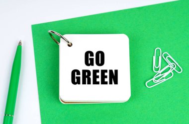 Ekoloji ve endüstri kavramı. Beyaz bir yüzeyde yeşil bir kağıt, bir kalem ve üzerinde 