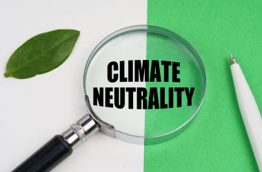 Ekolojik kavram. Beyaz-yeşil arka planda bir kalem, bir bitki yaprağı ve içinde iklim tarafsızlığı yazılı olan bir büyüteç bulunur.