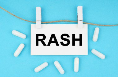 Mavi bir yüzeyde, raptiyeli bir iple, beyaz bir plaka var.