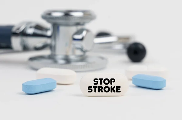Na białej powierzchni leżą pigułki, stetoskop i tabletka z napisem - STOP STROKE — Zdjęcie stockowe