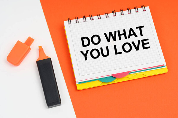 On a white-orange surface lies a marker and a notepad with the inscription - DO WHAT YOU LOVE
