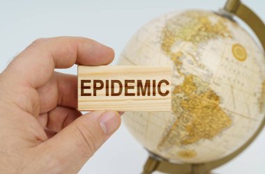 Bir adam elinde üzerinde EPIDEMIC yazan ahşap bir plaka tutuyor. Arka planda bir küre var..