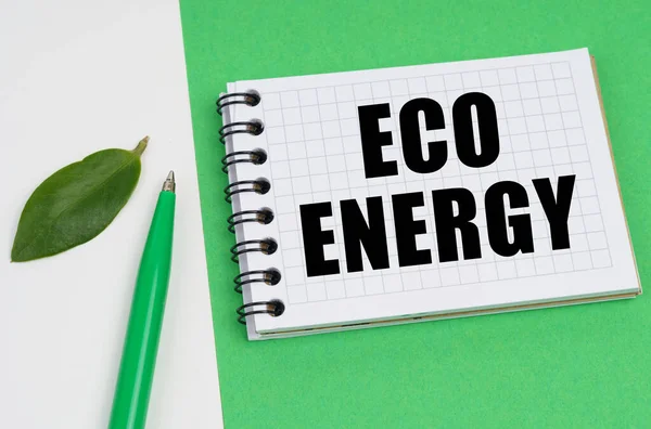 Na bílo-zeleném pozadí leží pero, list rostliny a poznámkový blok s nápisem - Eco energie — Stock fotografie