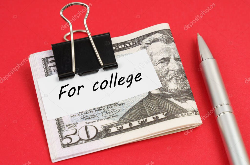 On a red background lies a pen and dollars clamped with a clip with the inscription on paper - For college