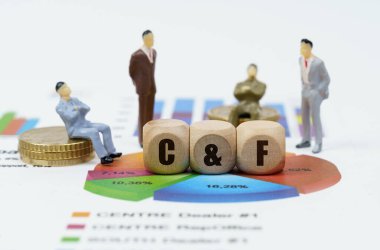 İş ve finans kavramı. Diyagramlı mali raporlar, iş adamlarının rakamları ve üzerinde C ve F yazılı tahta küpler.