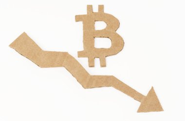Ekonomik kriz kavramı. Beyaz bir yüzeyde, aşağı ok ve bitcoin sembollü bir grafik. Sembol, ok ve grafik kartondan yapılmıştır